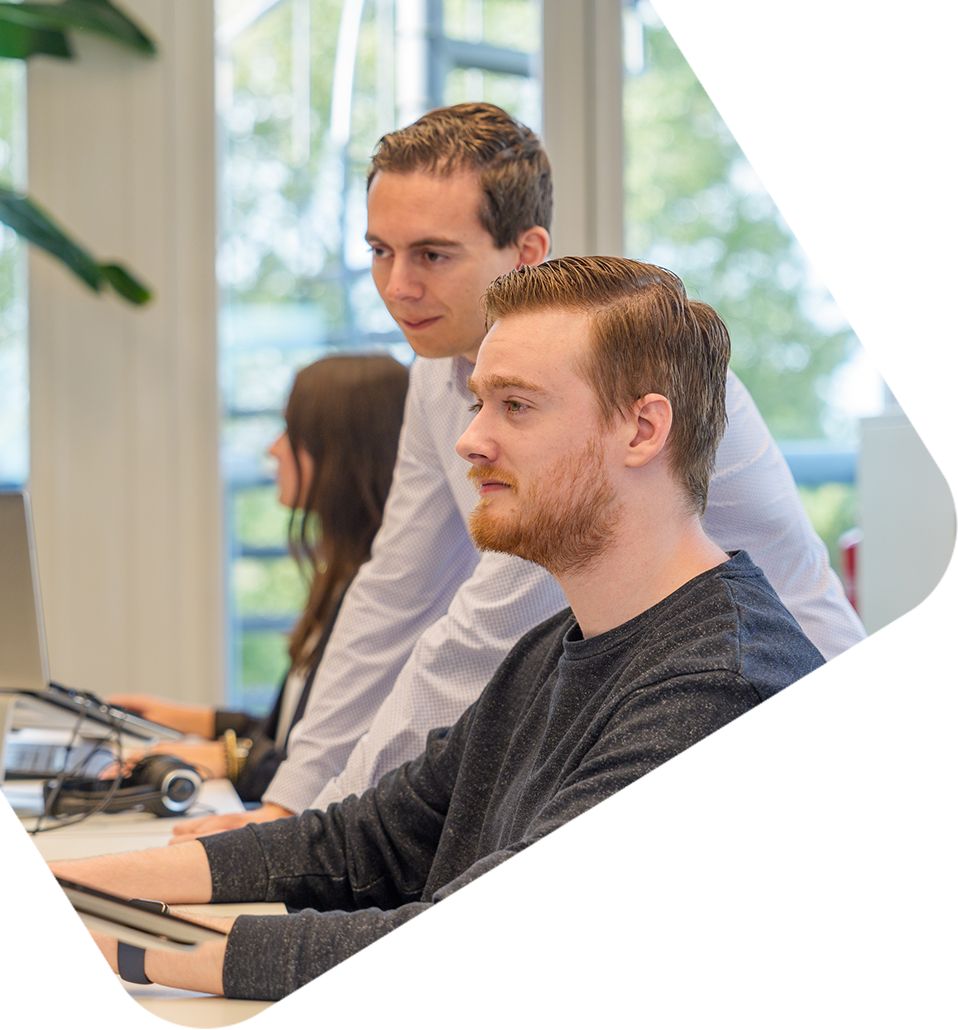 Man en collega over computer werkend aan AI‑gestuurde PIM‑integratie
